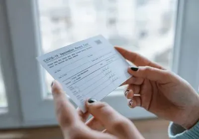 Woman holding a CDC COVID-19 vaccination card with both hands.